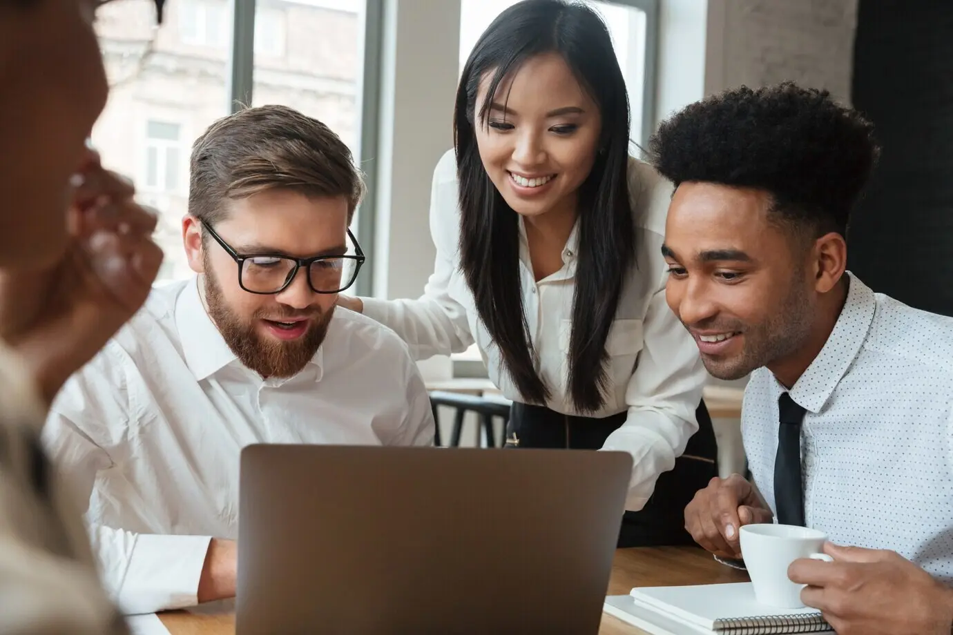 Jóvenes colegas de negocios felices usando una computadora portátil.