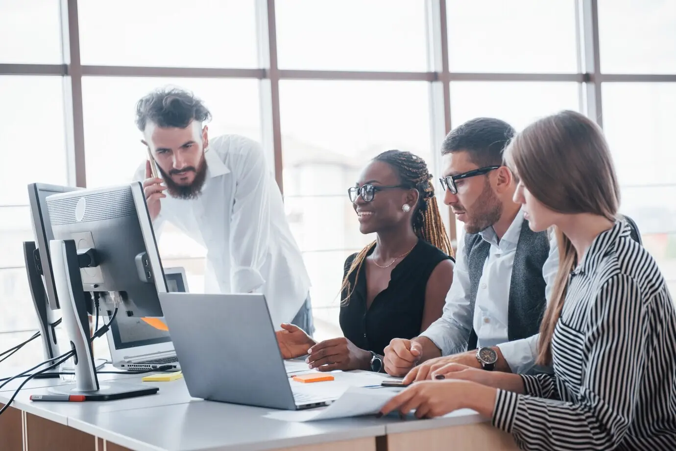 Empleados jóvenes sentados en una mesa de oficina utilizando un portátil, concepto de reunión de lluvia de ideas de trabajo en equipo.